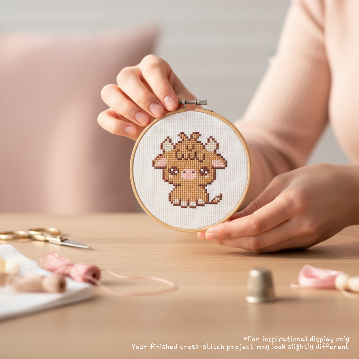 Finished kawaii Highland cow cross stitch held in a small hoop