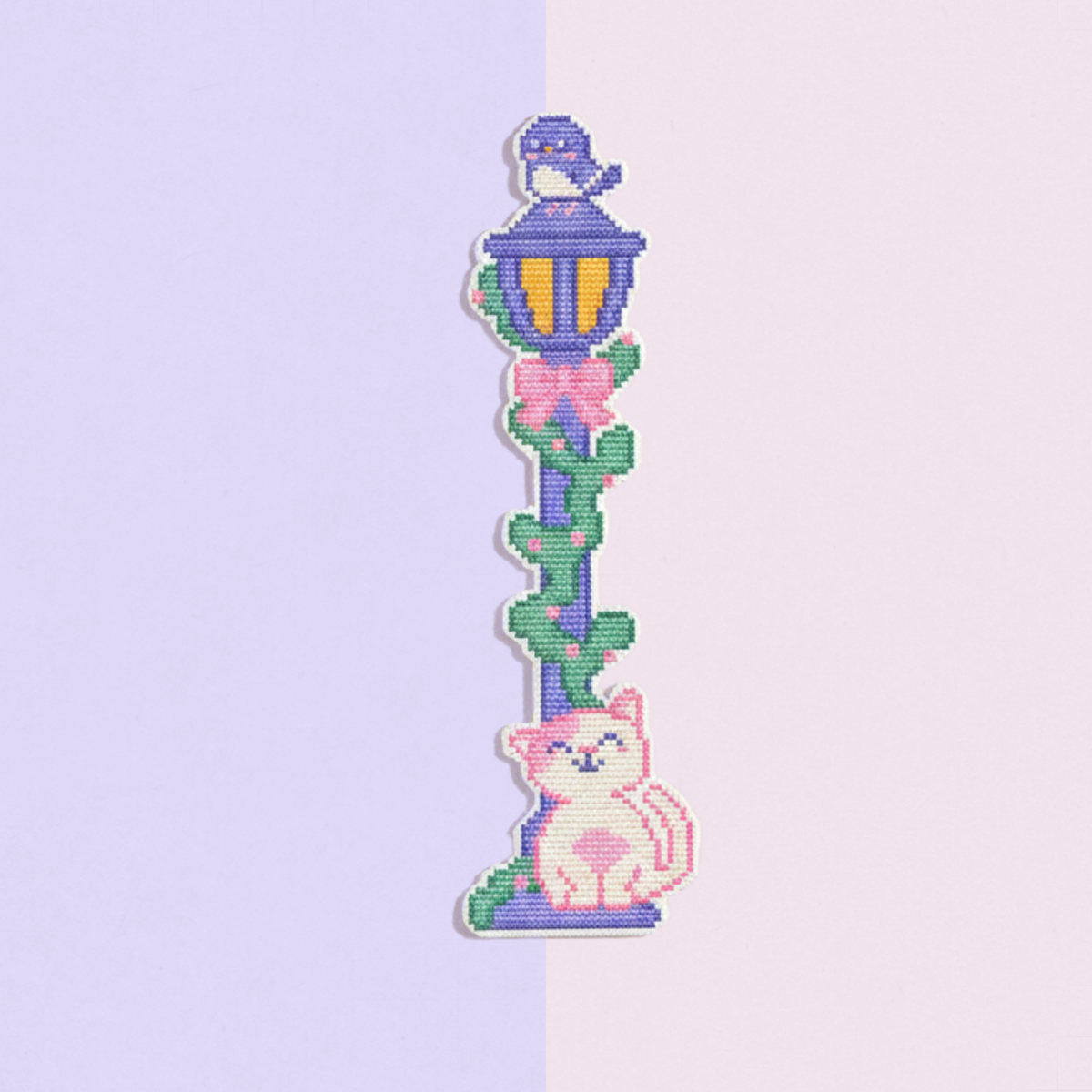Finished street lamp and cat cross stitch bookmark on a lavender and pink background