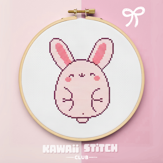 Pink bunny cross stitch design displayed in a wooden embroidery hoop