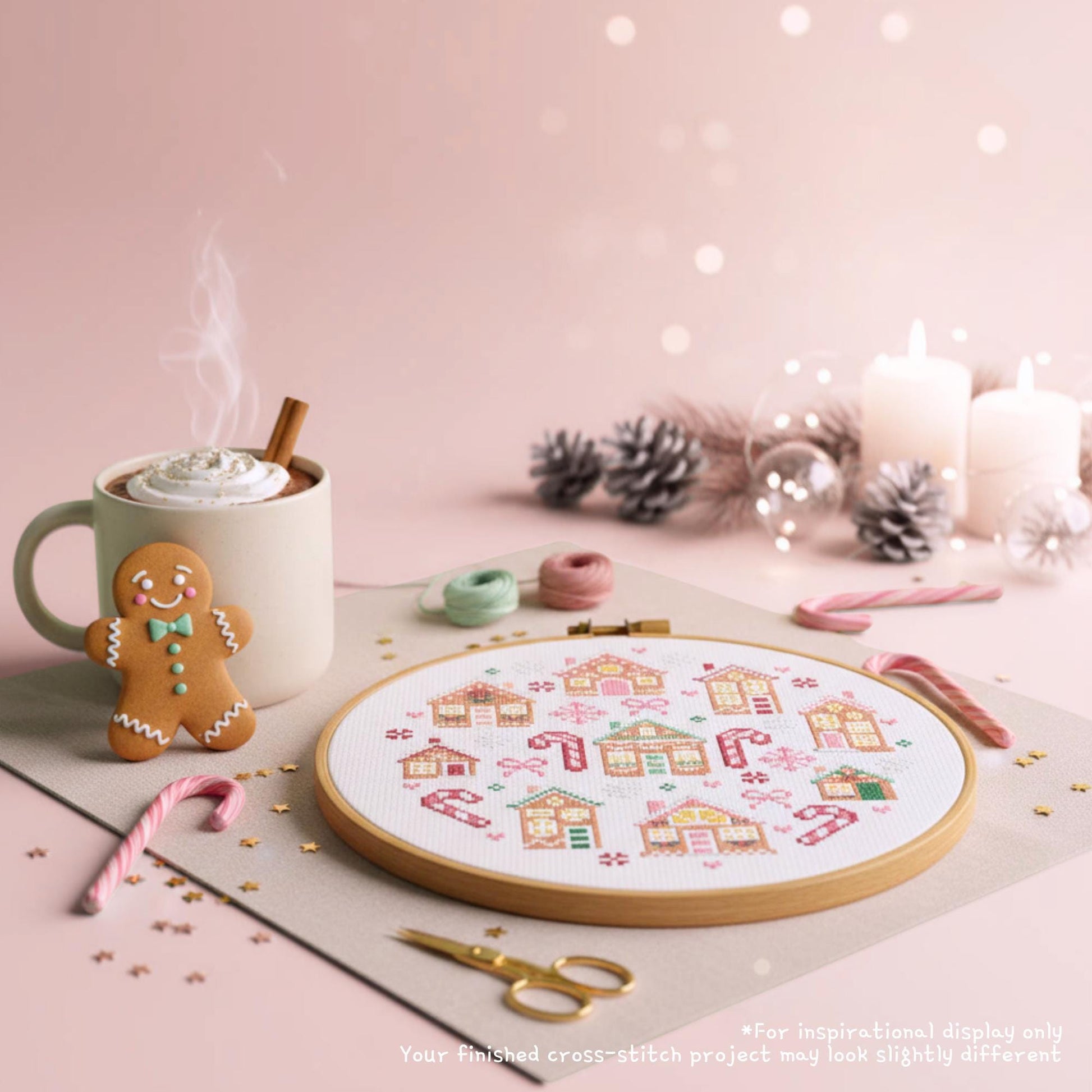 Finished gingerbread house cross stitch village in a hoop with candy canes, scissors and a gingerbread biscuit